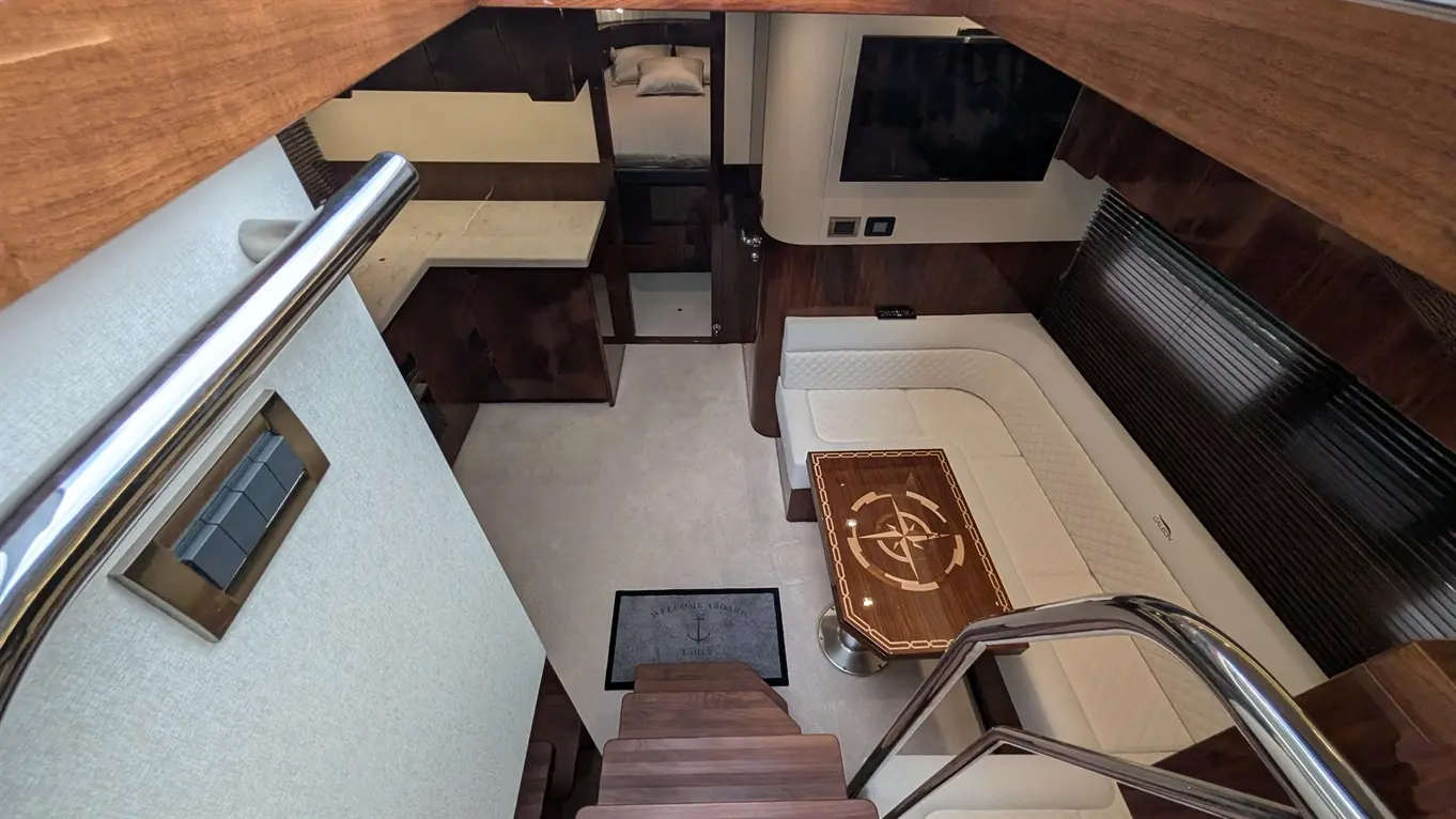 Interior view of a luxurious yacht cabin featuring a sofa, wooden table with a compass design, and a welcoming mat.
